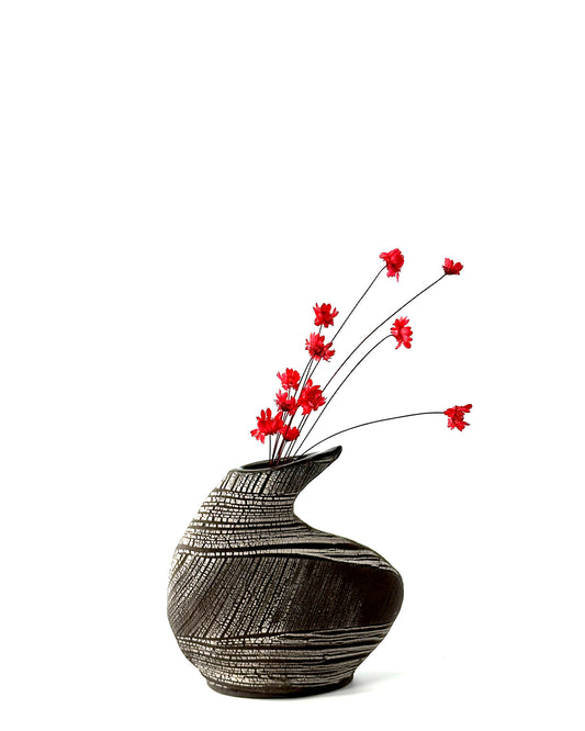 Black textured vase with red flowers on a white background