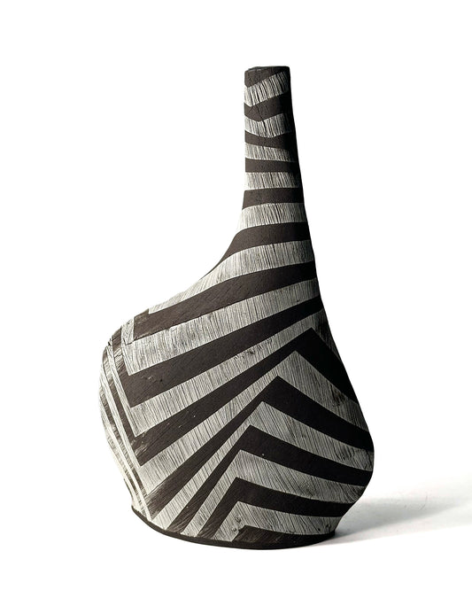 Sassy Vase by Yael Braha. Slanted hand built ceramic vase with black and white zig zag surface decorations, against a white background.