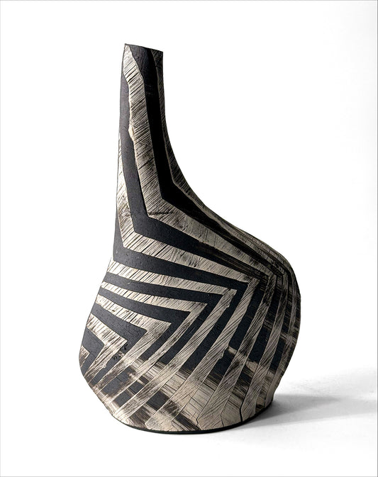 Sassy Vase by Yael Braha. Slanted hand built ceramic vase with black and white zig zag surface decorations, against a white background.