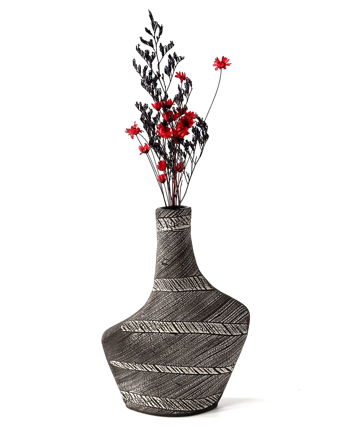 Decorative vase with black and white pattern containing red flowers on a white background