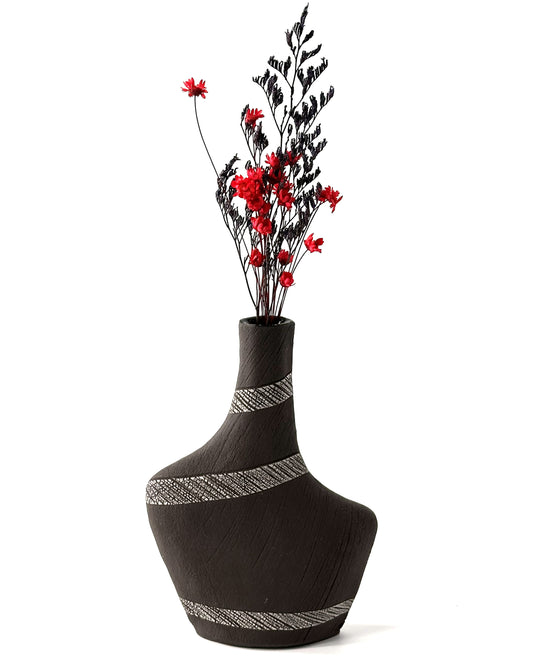 Black vase with decorative patterns and red flowers on a white background