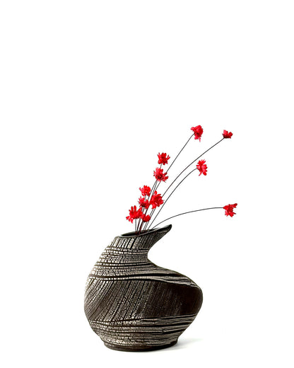 Black textured vase with red flowers on a white background
