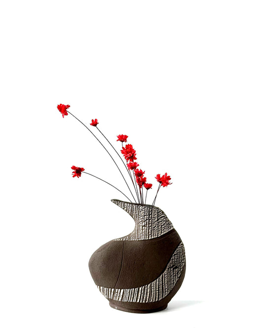 Decorative vase with black and white pattern and red flowers on a white background